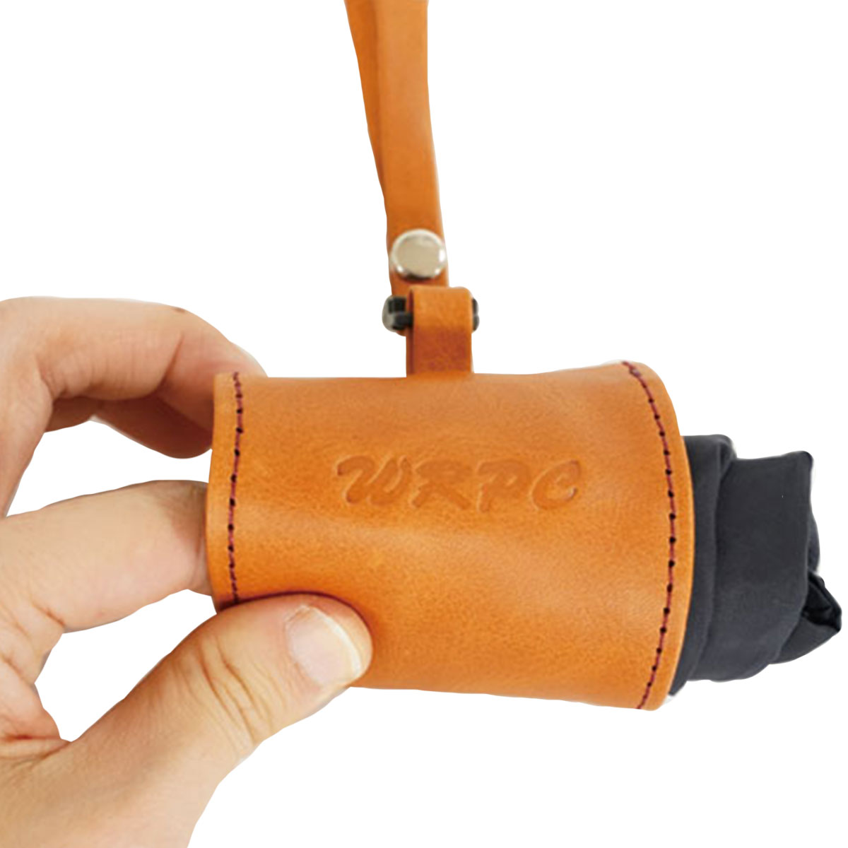 Tan leather cylindrical pouch held by fingers, with a strap and metal rivet visible above the opening.