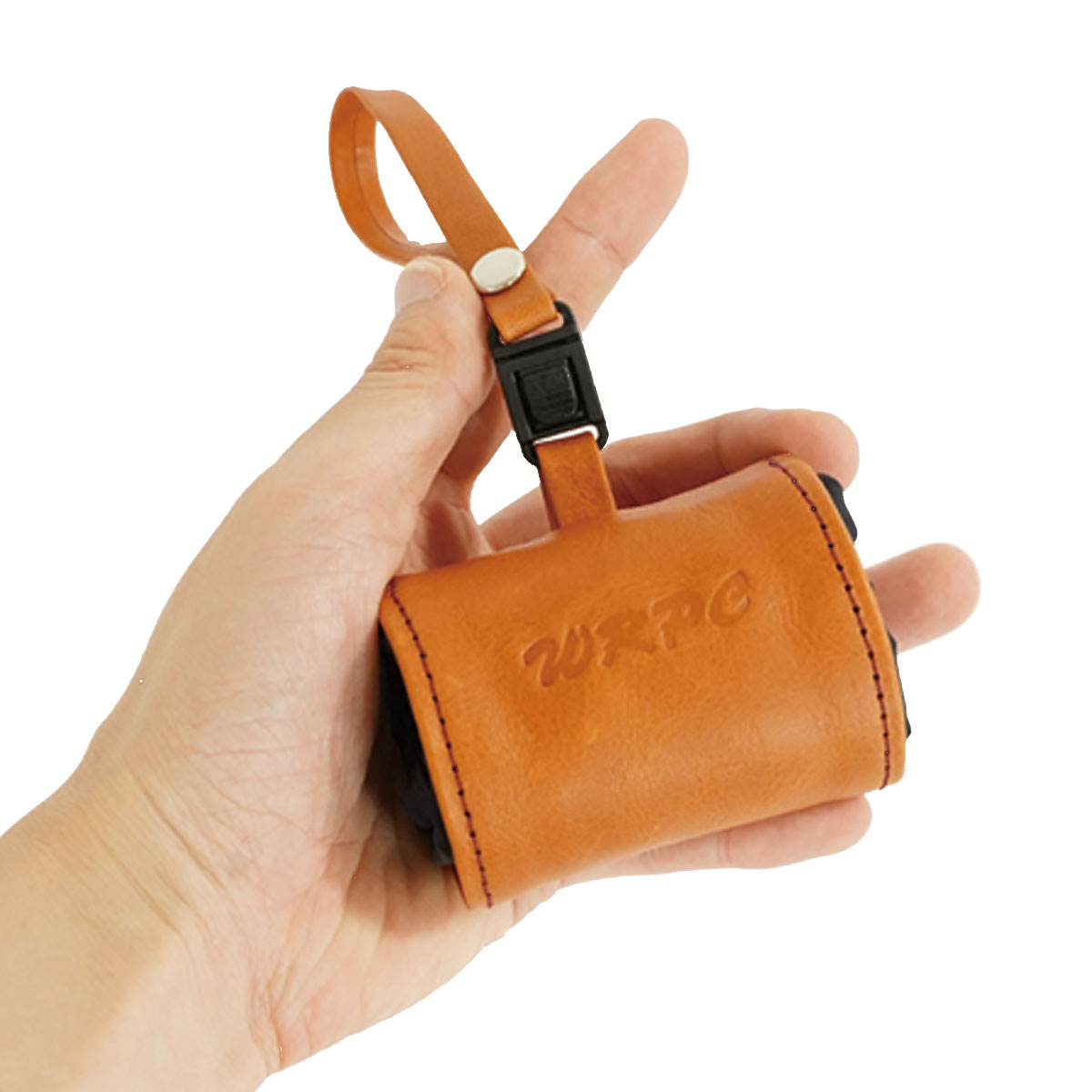 Hand holding a small tan leather pouch with a looped strap and black buckle attachment