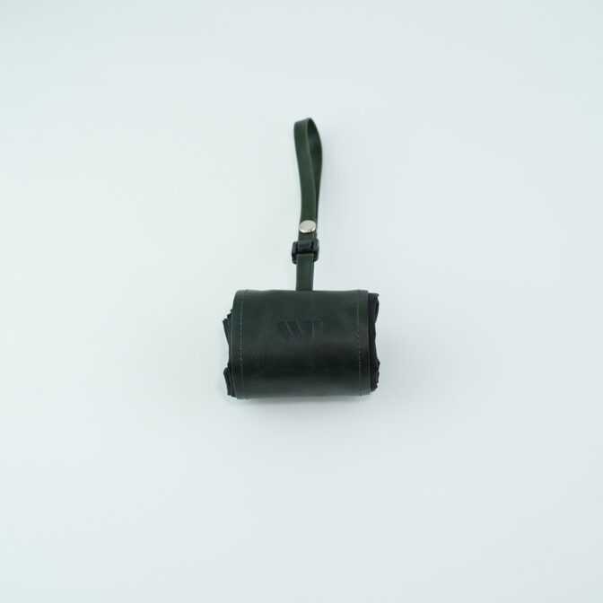 Dark green leather pocket bag with a short wrist strap, centered on a pale blue background.