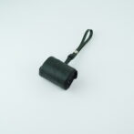 Small black leather roll-up pouch with a green strap on a pale blue background.