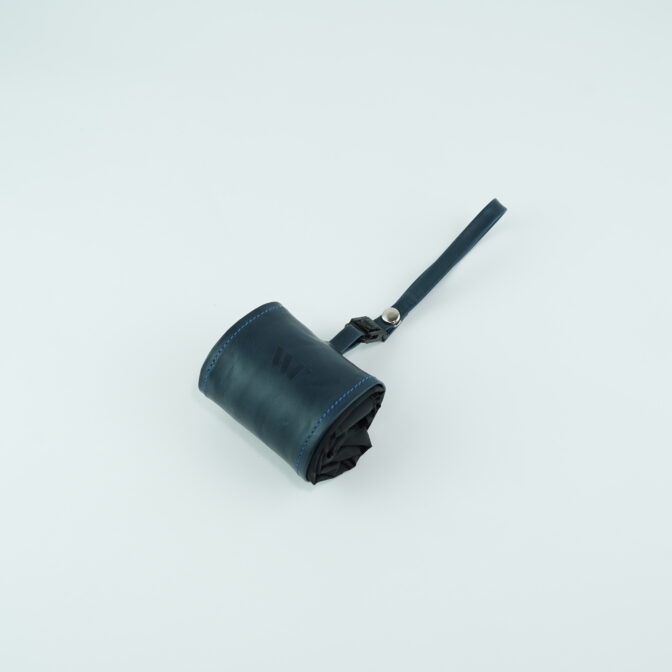 Rolled dark blue leather pouch with a wrist strap on a light background, partially unrolled to show stitching detail.