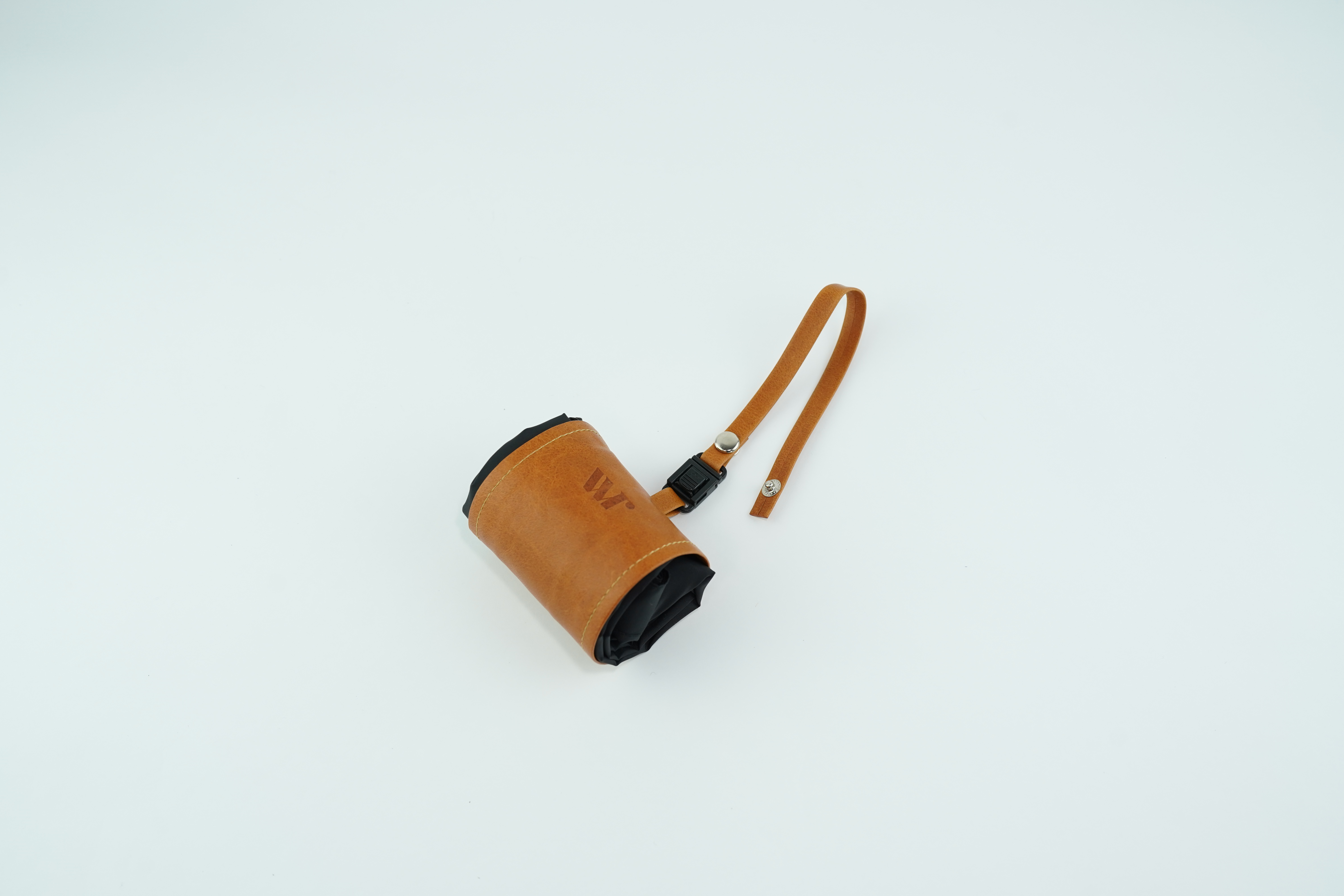 Tan leather handbag with a curved shoulder strap resting on a pale surface