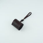 Small burgundy leather pouch with a matching wrist strap on a pale surface, likely a compact wallet or case.