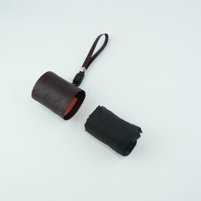 Brown leather cylindrical pouch with red stitching and a looped brown strap on a light background