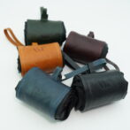 Assorted mini leather pouches in blue, orange, green, and burgundy with stitched edges and embossed logos on each front.